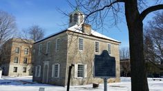 an old stone building with a clock tower on top in the middle of snow covered ground