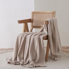 a chair with a blanket on it sitting in front of a white wall and floor