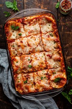 a casserole dish with meat, cheese and sauce in it on a wooden table