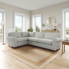 a living room with white walls and wooden floors, a large sectional couch in the center