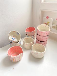 five bowls are lined up on a table in front of a framed photo and a window