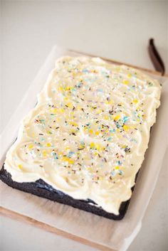 a cake with white frosting and sprinkles on it sitting on a napkin