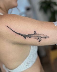 a woman's arm with a shark tattoo on the left side of her body