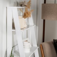 a white shelving unit with plants and vases on it's shelves in a living room