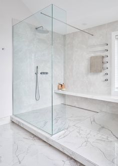 a bathroom with marble flooring and walls, including a walk - in shower area