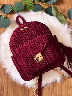 the burgundy crochet backpack is sitting on a white fur rug