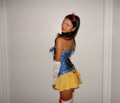 a woman dressed as snow white standing in front of a wall with her hands on her hips