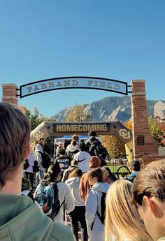 a group of people standing in front of a sign with the words home coming on it