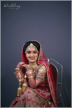 a woman in a red and gold bridal outfit sitting on a chair with her arms crossed