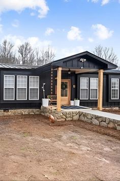 a small black house sitting on top of a dirt field