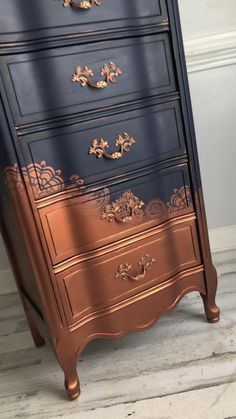 a black and gold chest of drawers sitting on top of a wooden floor next to a wall