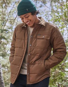 Man in a snap button-front medium brown collared jacket with left front pocket, wearing a green beanie. Button Jacket, Warm Brown, Jacket Buttons, Winter Holidays, Snap Button, Front Pocket