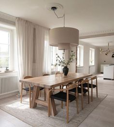 a dining room table with chairs and a lamp hanging over it in front of a window