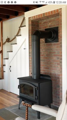 a black stove sitting in the middle of a living room next to a stair case