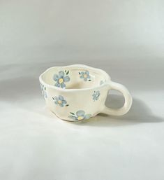 a white cup with blue and yellow flowers on the inside is sitting in front of a gray background