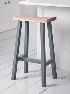 a wooden stool sitting on top of a white floor next to a kitchen countertop