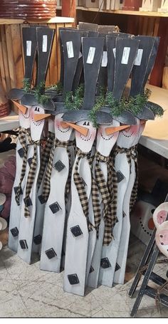 three snowmen are sitting on top of each other in the shape of poles with plants growing out of them