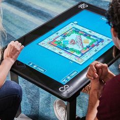 two people sitting in front of a table with a game on it