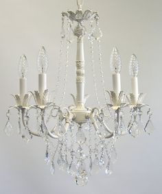 a white chandelier hanging from the ceiling with crystal drops on each light fixture