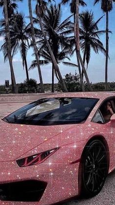 a pink sports car covered in stars and sparkles is parked on the street next to palm trees