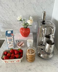 some strawberries are sitting on a counter next to a coffee maker and milkshake