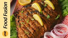 grilled fish with lemons and onions on a plate next to lettuce