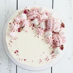 a white cake with pink frosting and sprinkles sitting on top of it