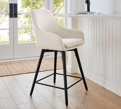 a white bar stool sitting on top of a hard wood floor next to a window