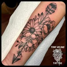 a black and white flower tattoo on the arm with an arrow in front of it