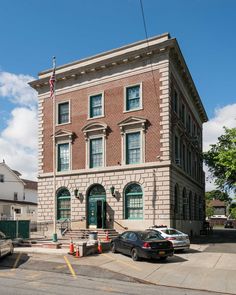 an old brick building on the corner of a street with cars parked in front of it