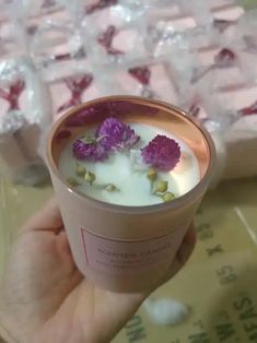 a hand holding a cup filled with liquid and flowers