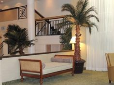 a living room filled with furniture next to a stair case and potted palm tree