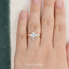 a woman's hand with an engagement ring on top of her finger, and the other hand is wearing a wedding band