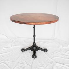 a round wooden table with black iron legs on a white background in front of a white backdrop