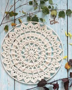 a white doily sitting on top of a wooden table next to leaves and branches