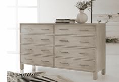 a white vase sitting on top of a wooden dresser next to a zebra print rug