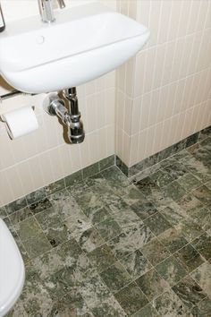 a white sink sitting next to a toilet in a bathroom under a faucet