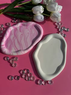 some pink and white items on a pink surface with flowers in the background, including a soap dish