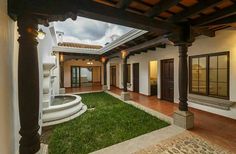 an outdoor courtyard with grass and stone steps leading to the front door, surrounded by columns