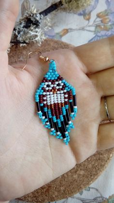 a hand holding a pair of beaded earrings