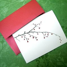 a red envelope with a white card on it and a branch with berries painted on it