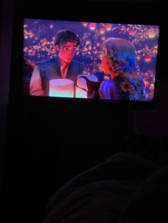 a man and woman sitting in front of a tv screen