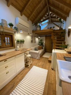 a kitchen and living room with wood floors, white cabinets and wooden ceilinging is shown