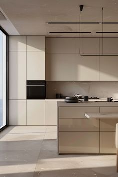 a modern kitchen with an island countertop and white cabinetry, along with a large window overlooking the ocean