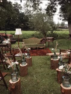 an outdoor seating area with chairs, tables and vases on stumps in the grass