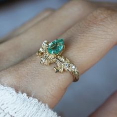 a close up of a person's hand with a green ring on their finger