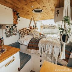 the interior of a camper with lots of pillows and blankets hanging from the ceiling