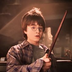 a boy with glasses holding a harry potter wand