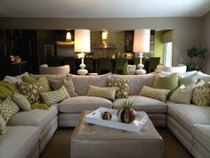 a living room filled with lots of furniture and pillows on top of couches in front of a fireplace