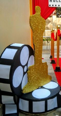 an oscar statue sitting on top of a black and white box with gold glitter around it